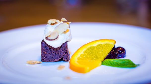 dessert A small square of flourless chocolate cake is elevated by the addition of fresh fruit and mint.