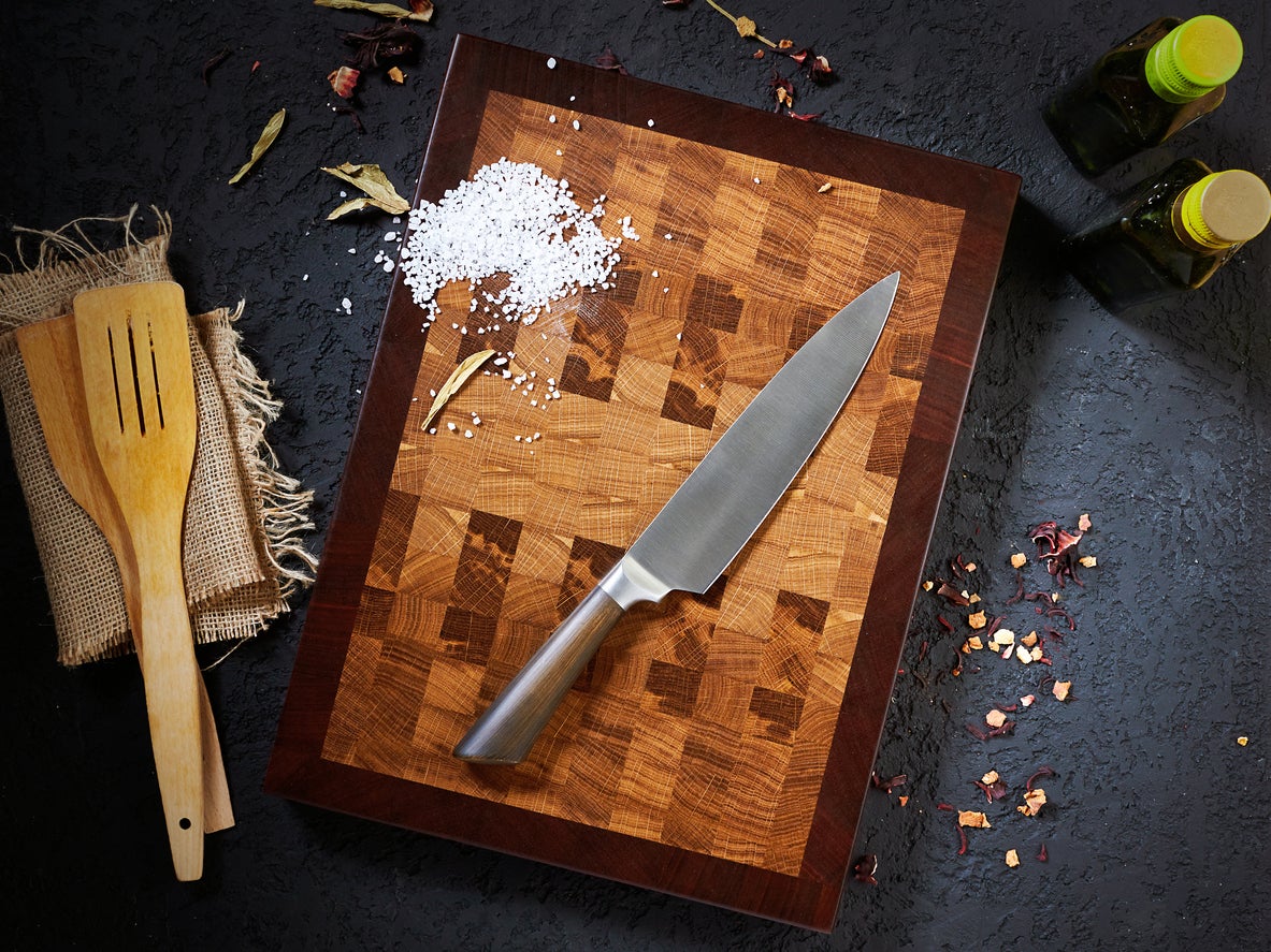 Top view beautiful cutting wooden board and chef knife, salt and olive oil on a dark background.