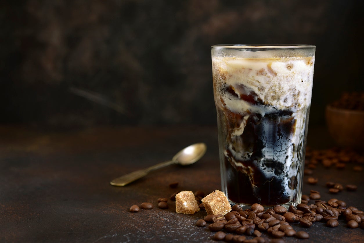 Homemade delicious iced coffee in a tall glass on a dark slate, stone or concrete background.