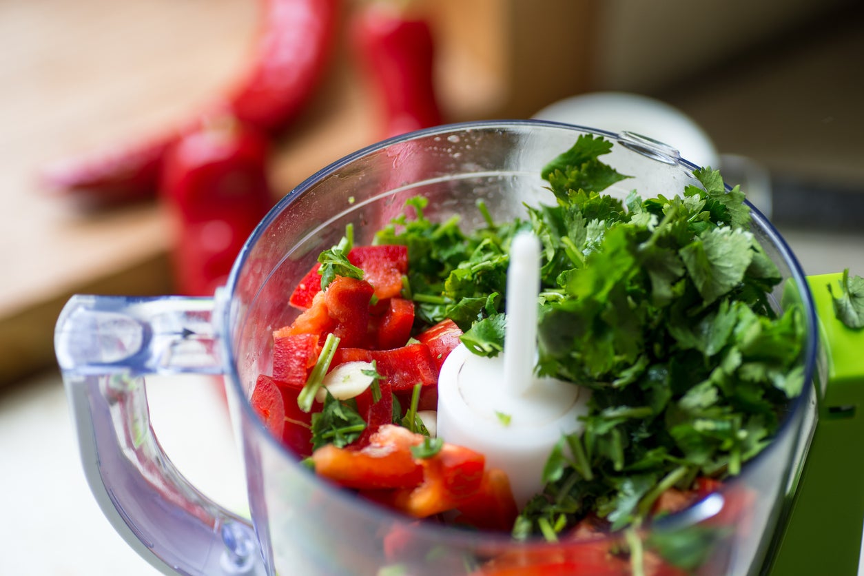 Blender with fresh bell pepper and cilantro on and kitchen table.