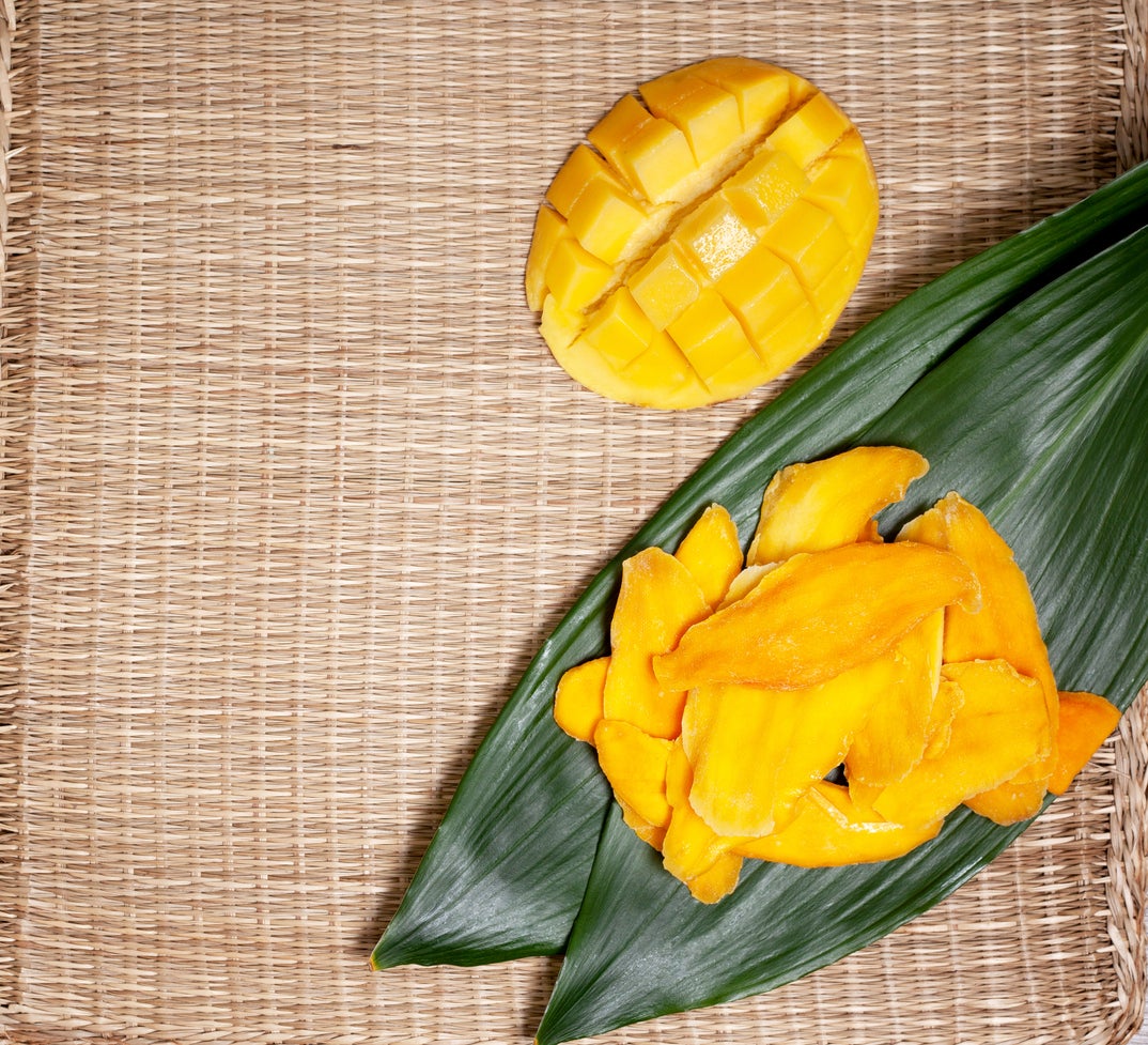pieces of dried mango, fresh mango on a straw background. view from above
