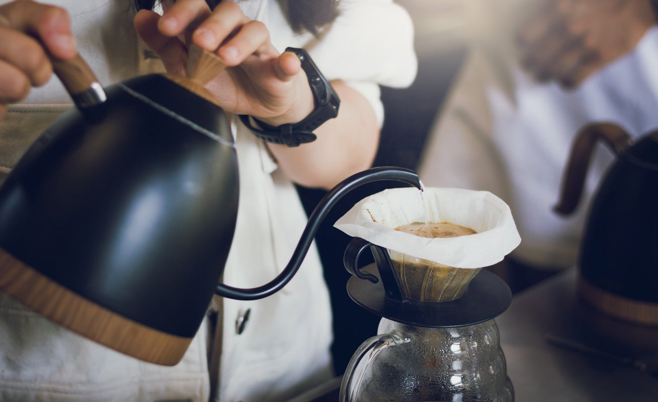 Barista poured hot water from the kettle into the glass jar to make coffee.