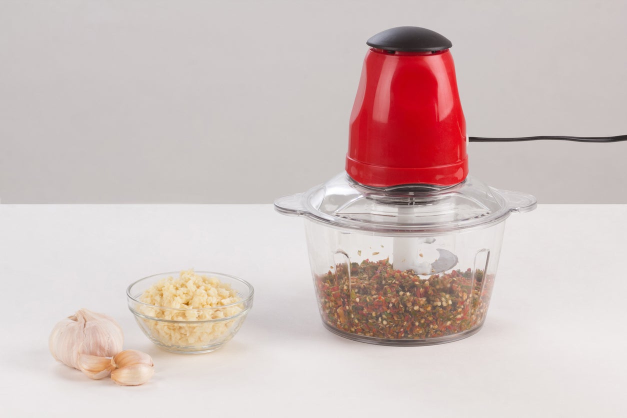 Food processor with chopped chilli inside isolated on white background