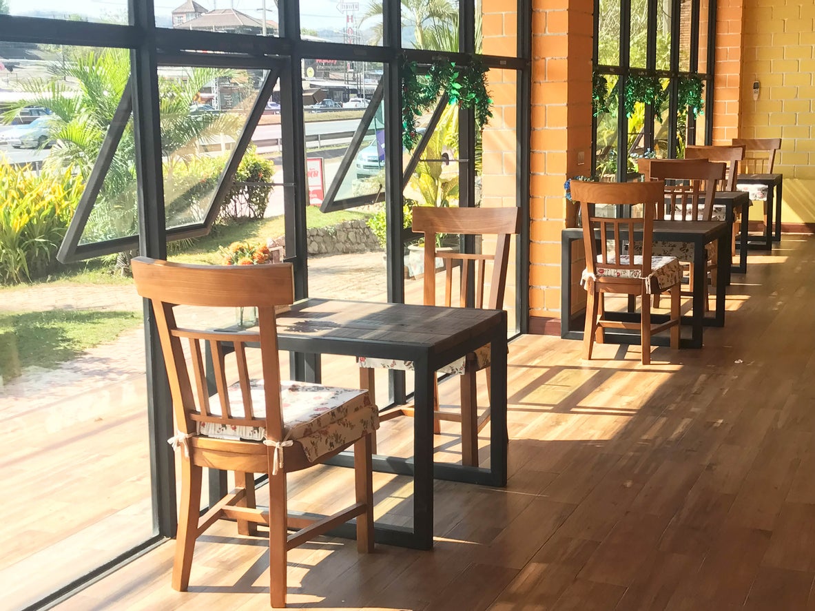 Classic wooden table and chair with cushion in restaurant or coffee shop over yellow brick wall and sun light