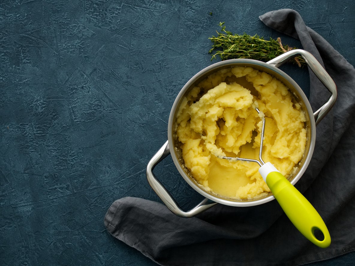 Mashed potatoes in bowl on dark stone blue table, rosemary, napkin, top view
