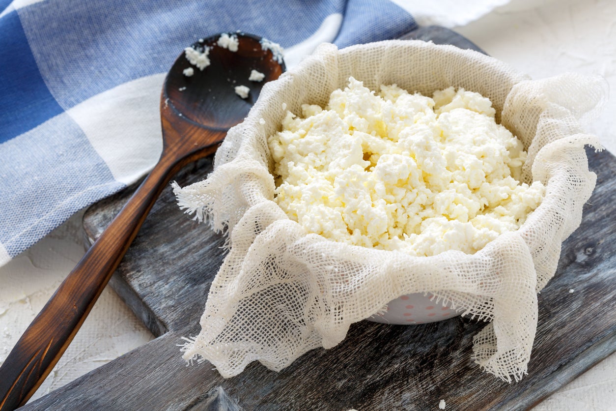 Homemade fresh cottage cheese in gauze and a bowl on the table with linen.