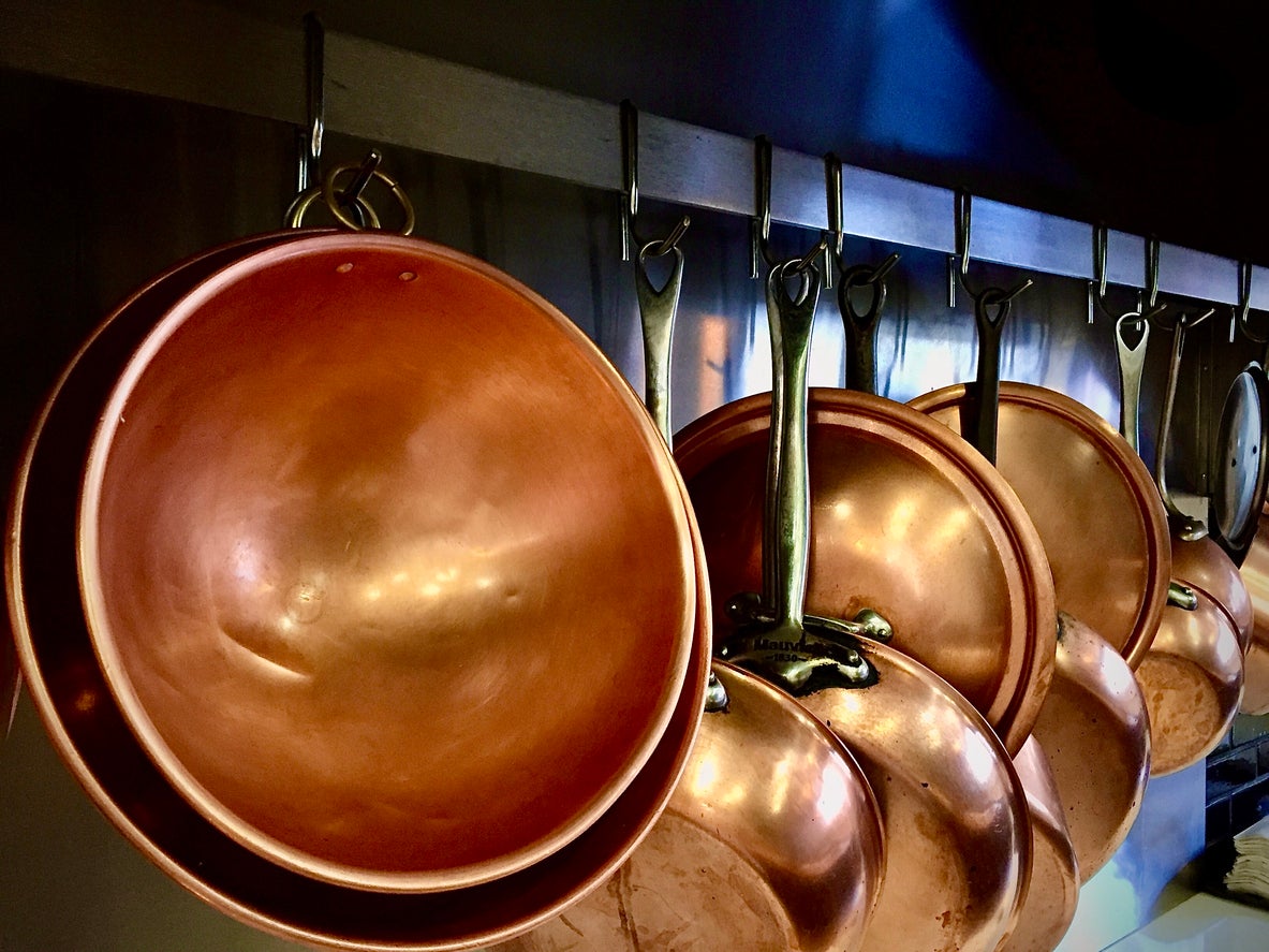 A kitchen ready for the evening rush, hanging copper bowls and sauté pans