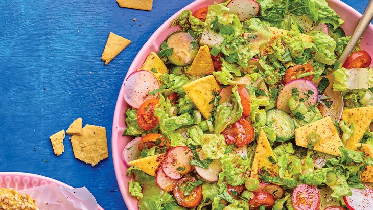 Pink plate of fattoush salad with chickpea crackers on a blue background