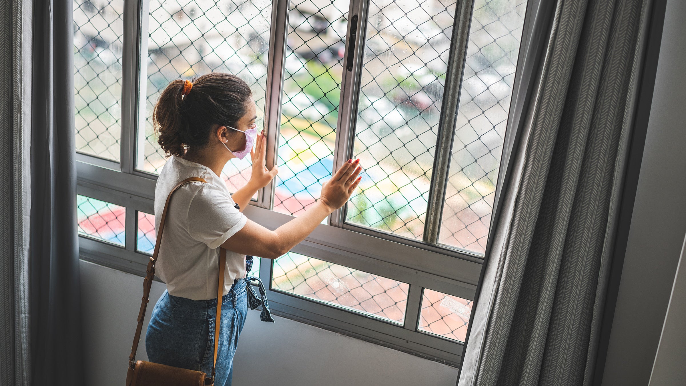 Masked woman looking out a window