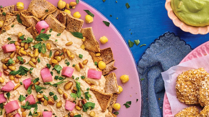 A pink plate of hummus fatteh on a blue background