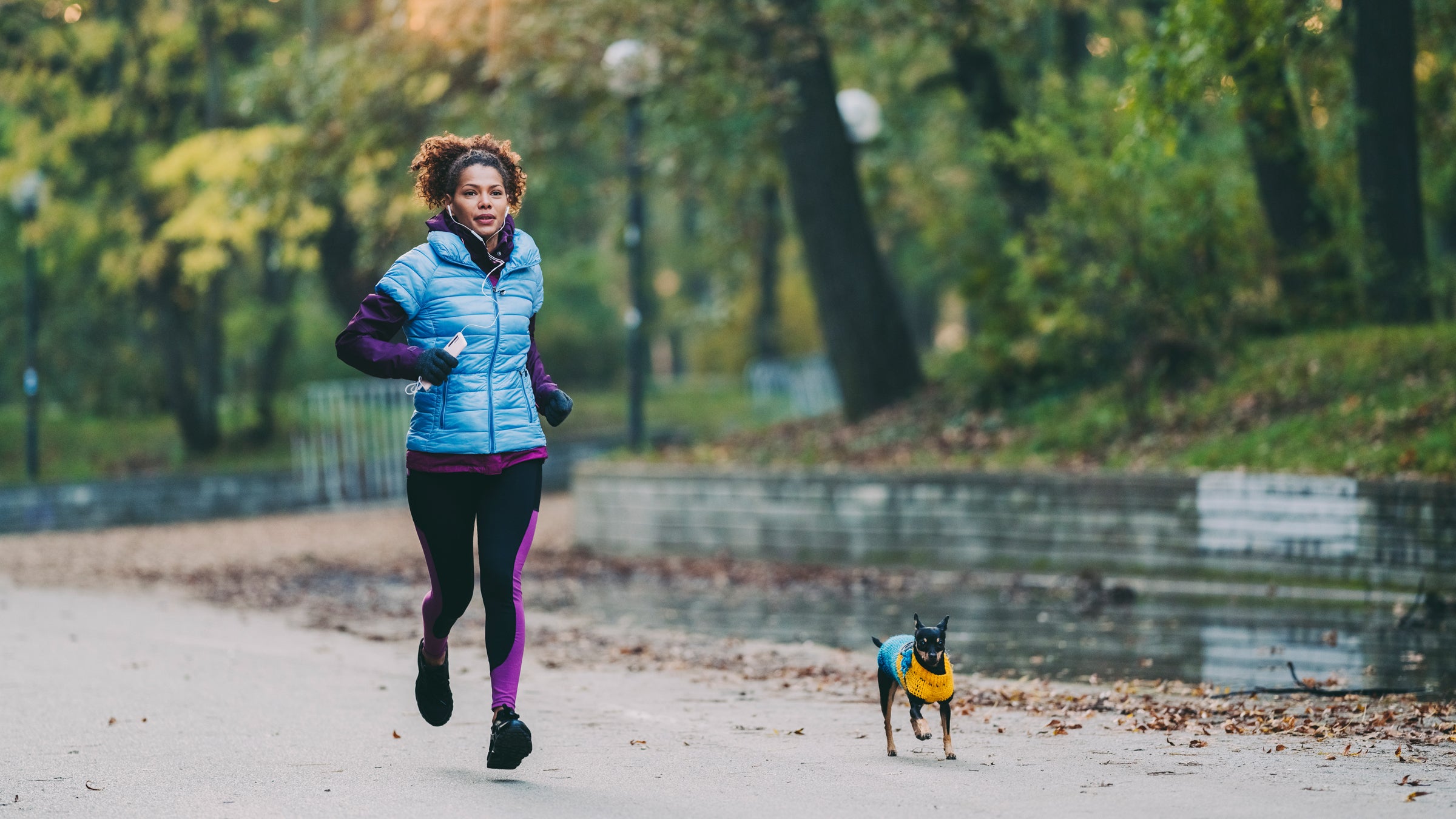 Woman running at a park with her mini pinscher